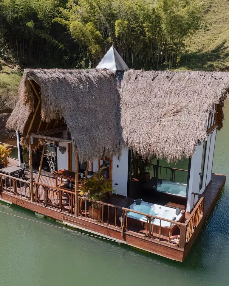 Cabaña de techo de paja construida sobre una plataforma flotante en el embalse, con jacuzzi en la terraza.