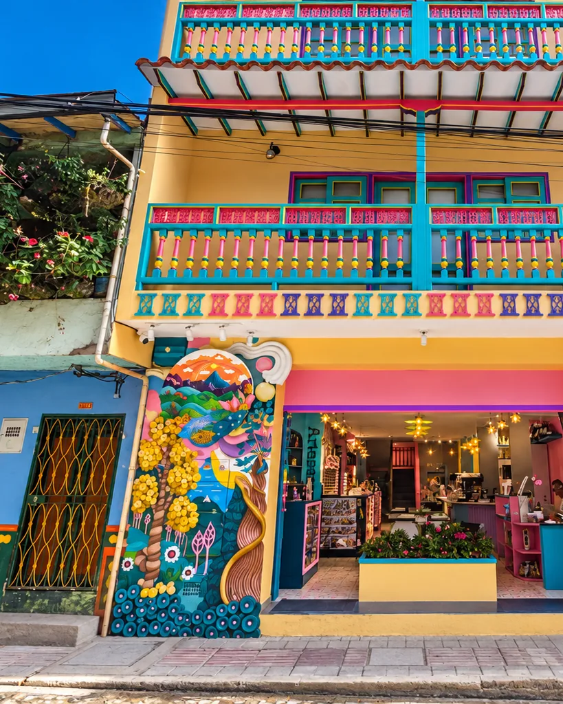 Fachada de un hotel del centro de Guatapé, pintada de amarillo, rosado y turquesa, con balcones y zócalos.